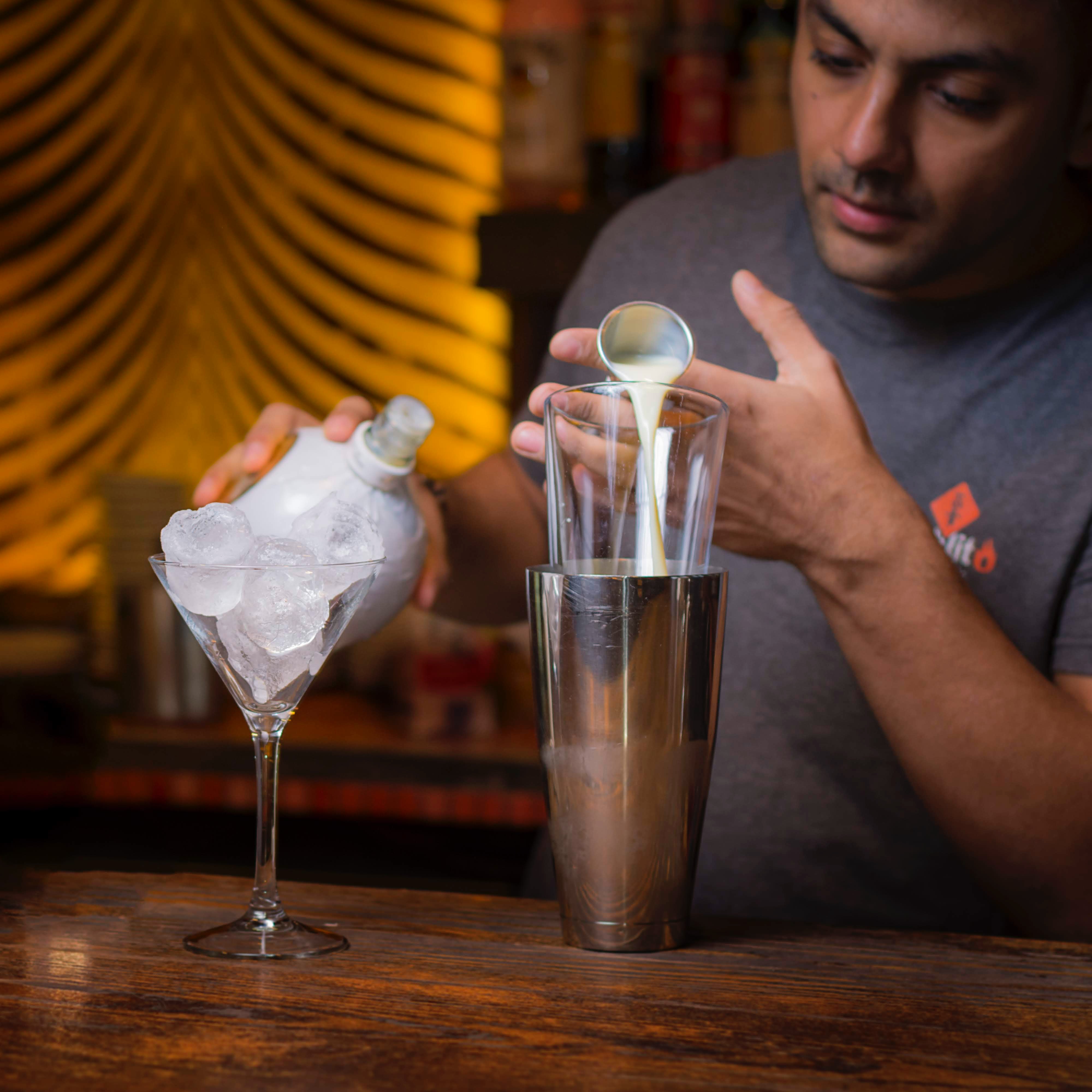 Barman en train de réaliser un cocktail au shaker, avec des glaçons