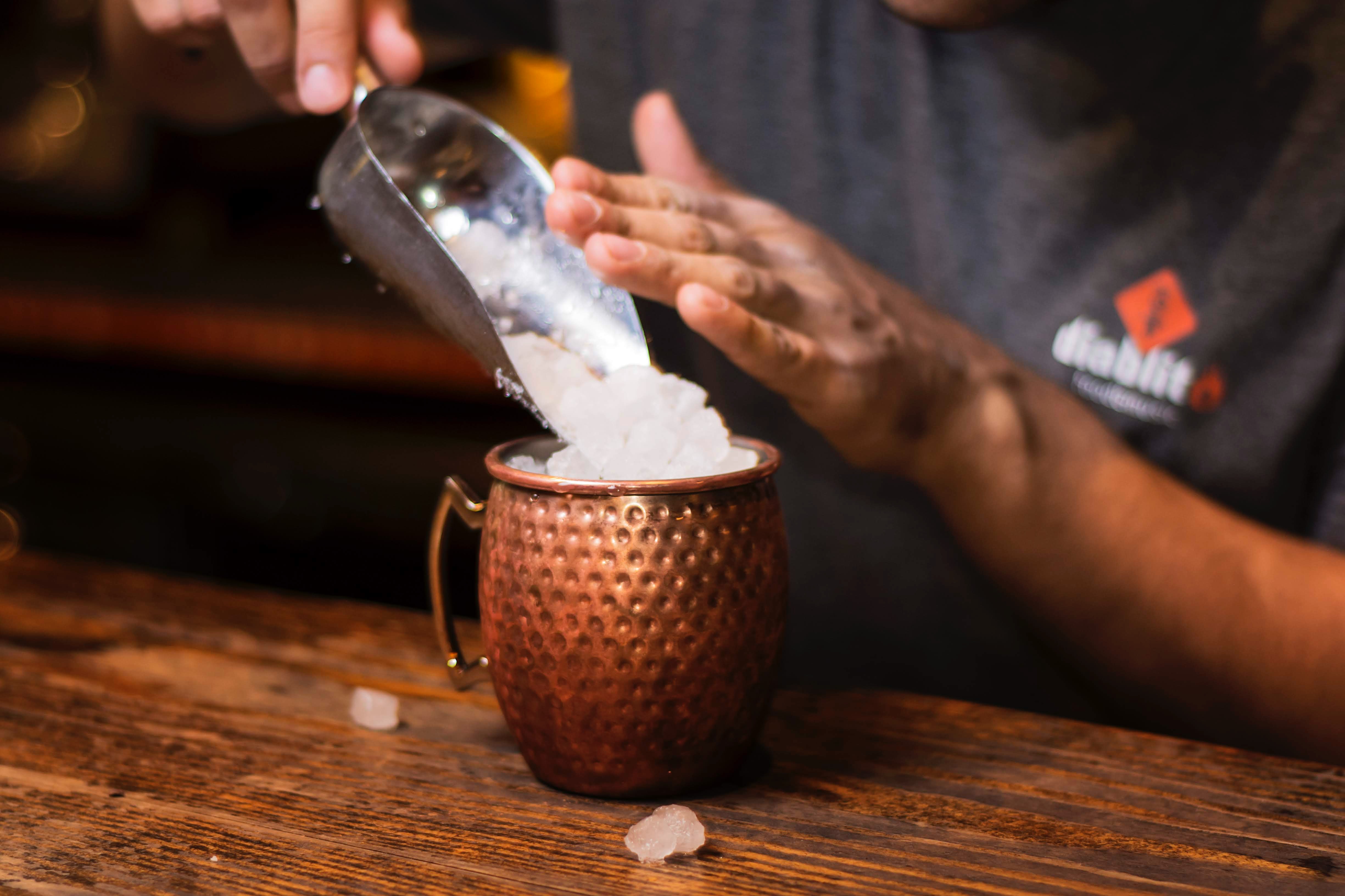 Glace pilée qu’un barman rajoute dans un cocktail Moscow Mule