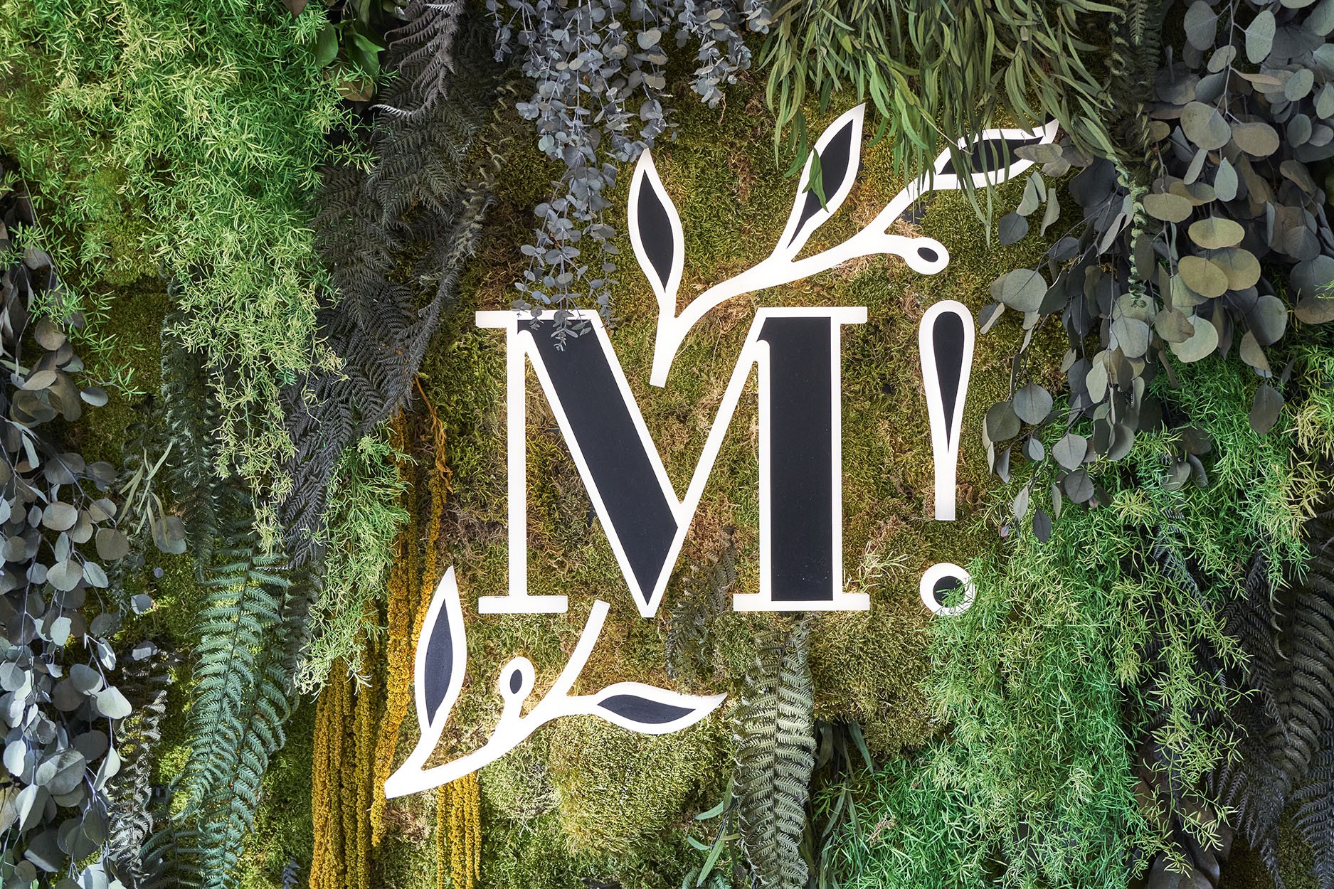Logo lumineux en lettre M avec végétaux